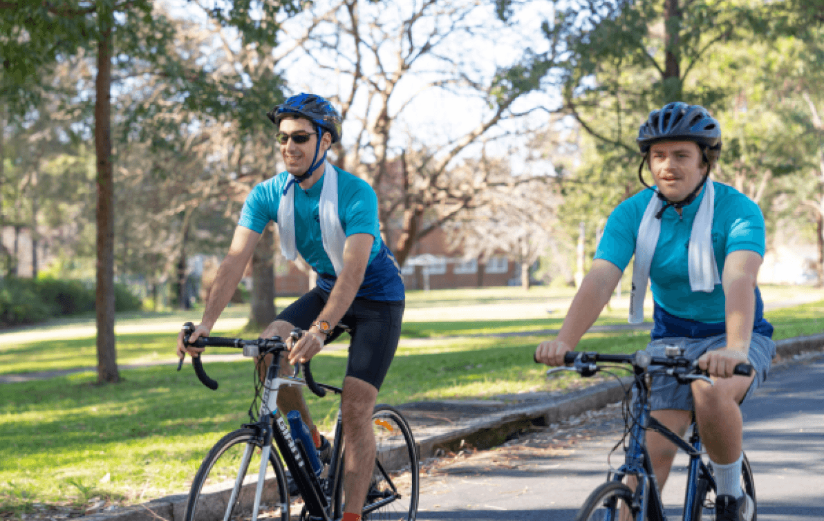 Two people cycling through a sunny park, smiling