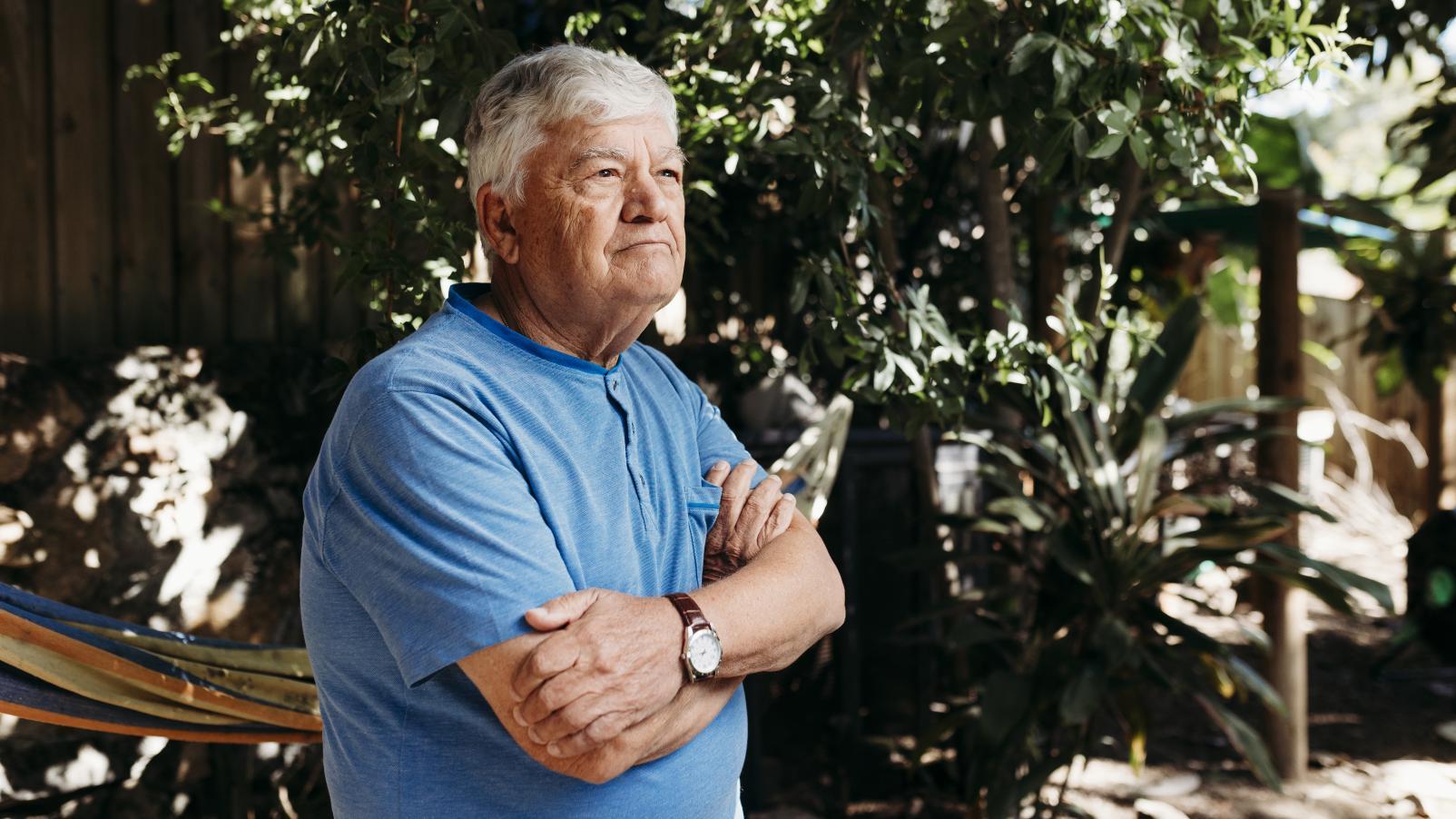 Image of a man in a garden wearing a blue shirt looking into the distance 