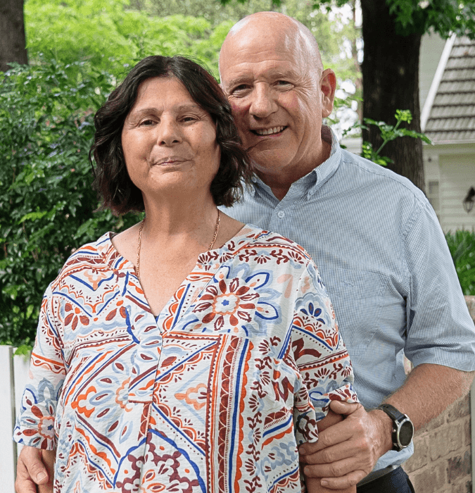 Laura and her partner Angus standing outside and looking at the camera and smiling.